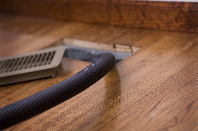 Detail image of a vacuum hose in an air duct for cleaning. Focus is on the hose.